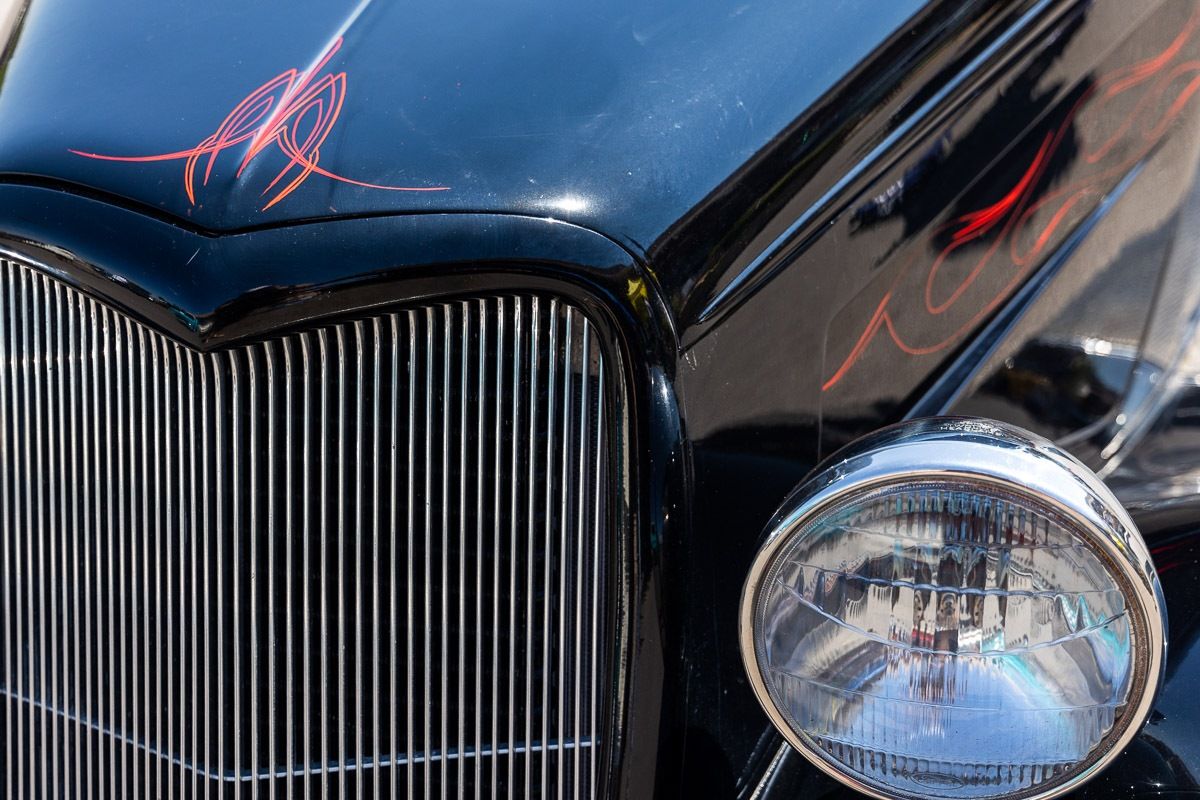 Chrome grille and headlight of a black hot rod with red pinstriping